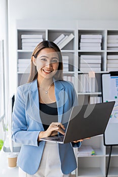 Asian businesswoman working at home office and analyzing financial documents and calculator, phone, laptop