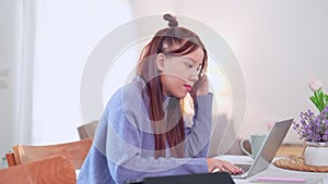 Asian businesswoman working from home, using her laptop at the table