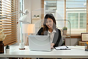 Asian businesswoman working with laptop computer and financial document at her workplace