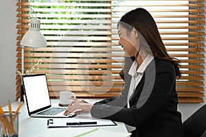 Asian businesswoman working with laptop computer and financial document at her workplace