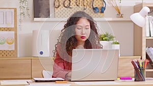 Asian Businesswoman working on laptop computer at home office.  Professional typing on laptop keyboard at workplace. Portrait of