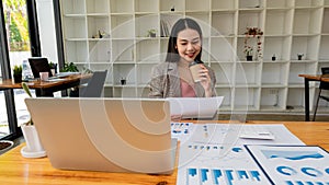 Asian businesswoman working, pointer graph, discussion and data analysis. Charts and graphs and using a calculator to calculate nu