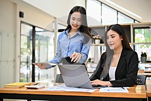 Asian businesswomen or financial analysts working on their financial and sales analysis together