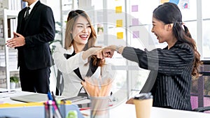 Asian businesswomen fist bump for the teamwork of business mergers and acquisitions for successful negotiation.
