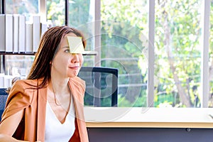 Asian businesswomen look and write a post-it note on their faces to relax and smile from work