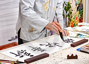 Asian caligraphy. The master of Chinese Caligraphy writes on rice paper characters and hieroglyphs that read Xin nian
