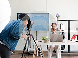 Asian camera man and pretty influencer recording live video about game product review with microphone and share screen from laptop