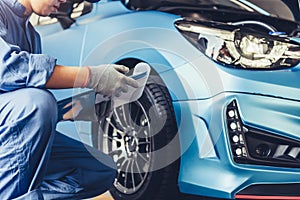 Asian car mechanic technician holding clipboard and checking to maintenance vehicle by customer claim order in auto repair shop