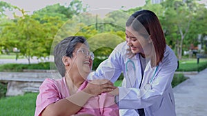 Asian careful caregiver or doctor hold the patient hand and encourage the patient in a wheelchair. Concept of happy retirement