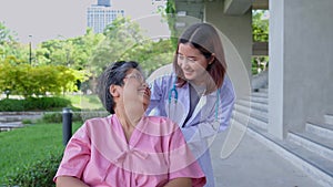 Asian careful caregiver or doctor hold the patient hand and encourage the patient in a wheelchair. Concept of happy retirement