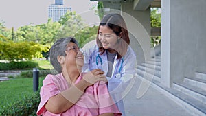 Asian careful caregiver or doctor hold the patient hand and encourage the patient in a wheelchair. Concept of happy retirement