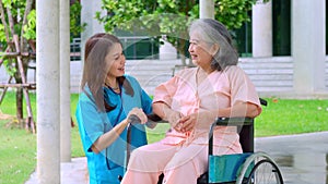 Asian careful caregiver or nurse taking care of the elderly Asian patient in a wheelchair. Concept of happy retirement with care