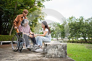 Asian careful caregiver or nurse taking care of the patient is hurting knee in wheelchair. Concept of happy retirement with care