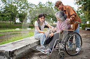 Asian careful caregiver or nurse taking care of the patient is hurting knee in wheelchair. Concept of happy retirement with care