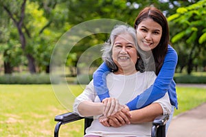 Asian careful caregiver or nurse taking care of the patient in a wheelchair.  Concept of happy retirement with care from a