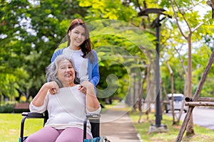 Asian careful caregiver or nurse taking care of the patient in a wheelchair.  Concept of happy retirement with care from a