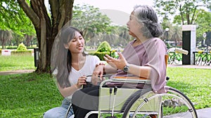 Asian careful caregiver or nurse taking care of the patient in a wheelchair.  Concept of happy retirement with care from a