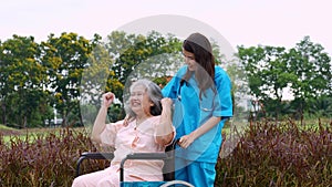 Asian careful caregiver or nurse taking care of the patient in a wheelchair.  Concept of happy retirement with care from a