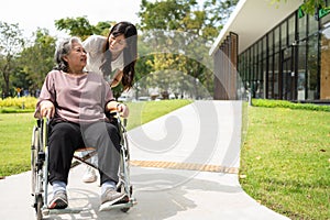 Asian careful caregiver or nurse taking care of the patient in a wheelchair. Concept of happy retirement with care from a