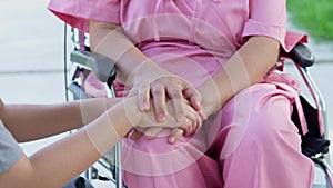 Asian careful caregiver or nurse taking care of the patient in a wheelchair. Concept of a happy retirement with care from a