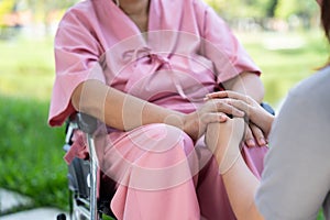 Asian careful caregiver or nurse taking care of the patient in a wheelchair. Concept of a happy retirement with care from a