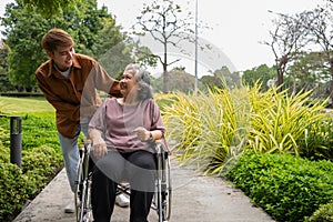 Asian careful caregiver or nurse taking care of the patient in a wheelchair. Concept of a happy retirement with care from a