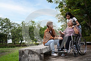 Asian careful caregiver or nurse taking care of the patient in a wheelchair. Concept of a happy retirement with care from a