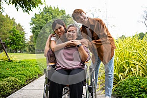 Asian careful caregiver or nurse taking care of the patient in a wheelchair. Concept of a happy retirement with care from a