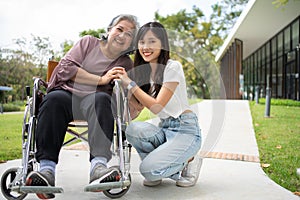 Asian careful caregiver or nurse taking care of the patient in a wheelchair. Concept of happy retirement with care from a