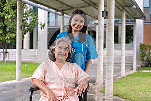 Asian careful caregiver or nurse taking care of the patient in a wheelchair. Concept of happy retirement with care from a