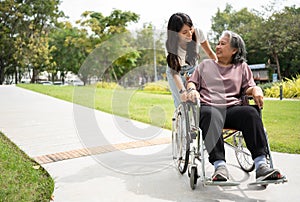 Asian careful caregiver or nurse taking care of the patient in a wheelchair. Concept of happy retirement with care from a