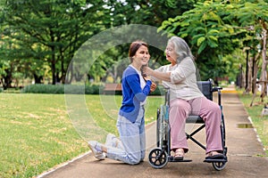 Asian careful caregiver or nurse taking care of the patient in a wheelchair. Concept of happy retirement with care from a