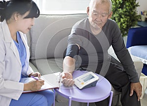Asian caregiver doctor examine older patient use blood pressure gauge