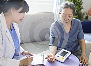 Asian caregiver doctor examine older patient use blood pressure gauge