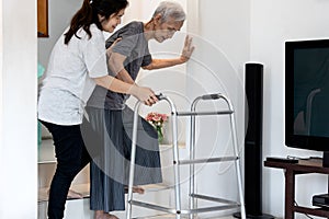 Asian caregiver helping to senior woman walking for safety in balance during the steps up and down the stairs or be careful