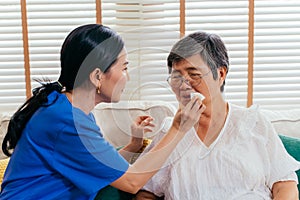 Asian caregiver wiping mouth of elderly patient