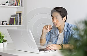 Asian Casual Businessman or Freelancer Working with Laptop in Home Office