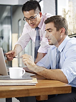 Asian and caucasian businessmen working together in office