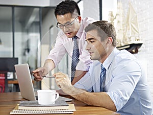 Asian and caucasian businessmen working together in office