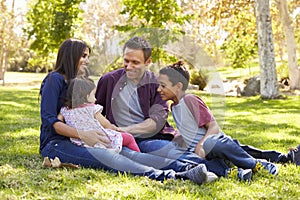 Asian Caucasian mixed race family sitting on grass in a park