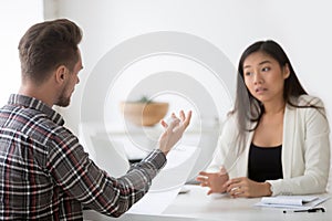 Asian and caucasian partners negotiating disagreeing about contr