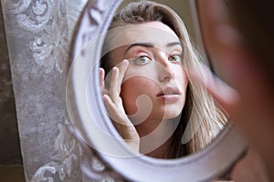 Asian caucasian woman girl unhappy touching her face an look at the mirror close up