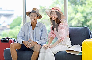 Asian cheerful male female lover couple traveler husband wife in casual summer vacation outfit with hat sitting smiling together