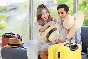 Asian cheerful male female lover couple traveler husband wife in casual summer vacation outfit with hat sitting smiling together