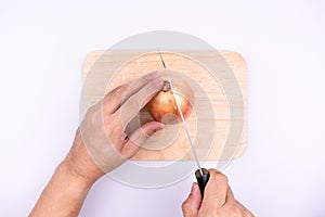 Asian chef`s hand is cutting onion with knife on chopping board.