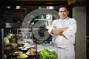 Asian chef smiling at camera in restaurant kitchen