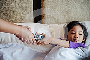 Asian Child On Bed Wants to Take Over Television Remote Control from His Parent Hands. Addiction or Parental Control Concept photo