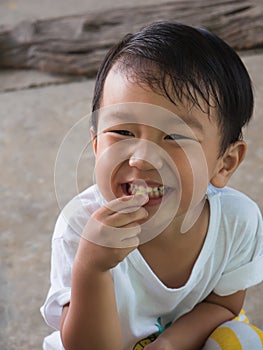 Asian child boy eating food with smiling happy funny close up face.