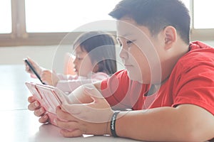 Asian child Boy and girls are addictive playing tablet and mobile phones photo