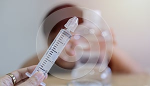 Asian child boy having stuffy nose,difficulty breathing,nasal wash,nose cleaning with syringe and saline. Selective focus at